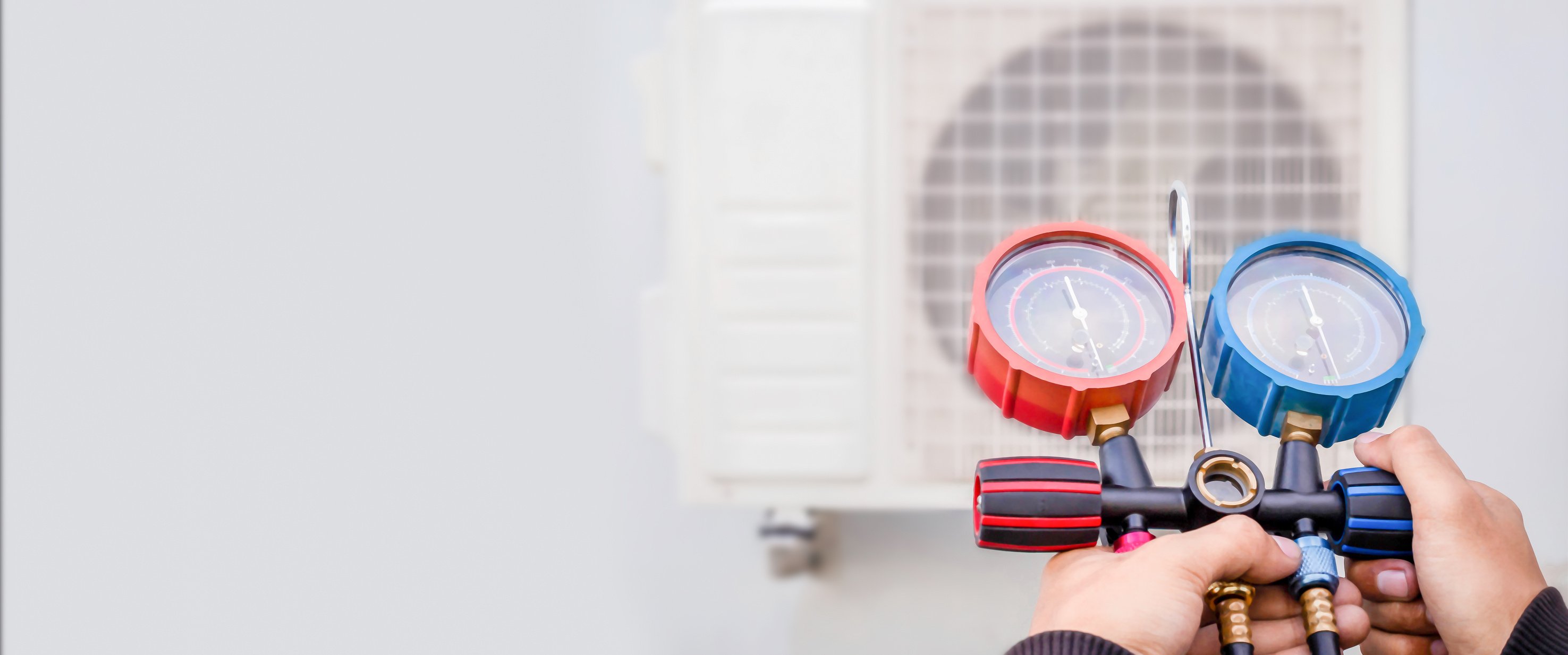 Air conditioning, HVAC service technician using gauges to check refrigerant and add refrigerant.